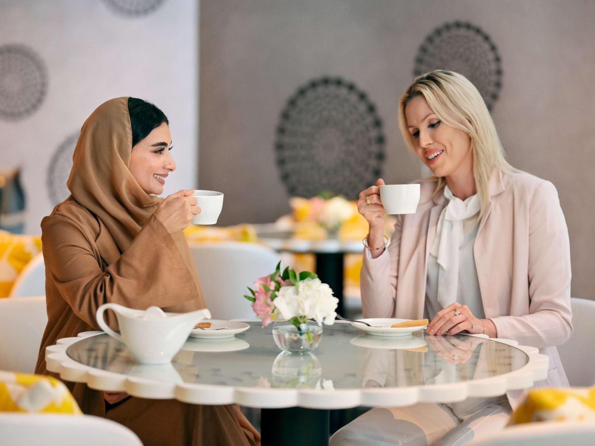 Moevenpick Hotel & Apartments Ghala Маскат Екстериор снимка Two women drinking coffee